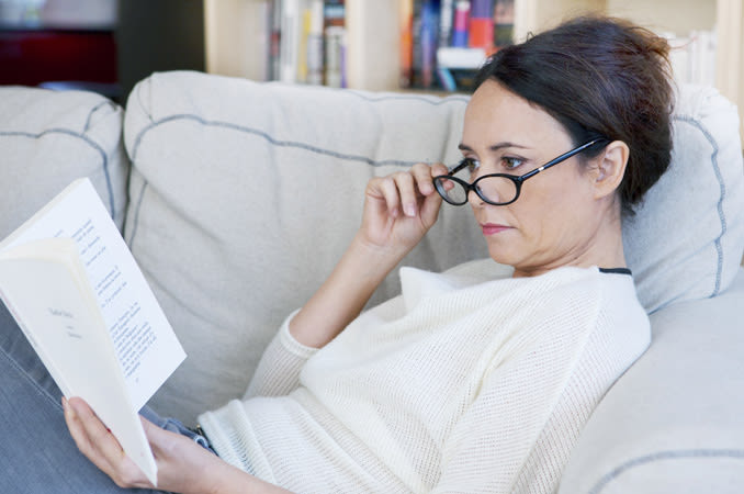 woman with spectacles reading a book